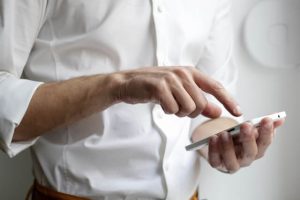 Closeup of a man in a white shirt holding an Android phone