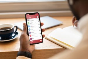 Image of person sitting at desk holding a phone with messaging app chats displayed