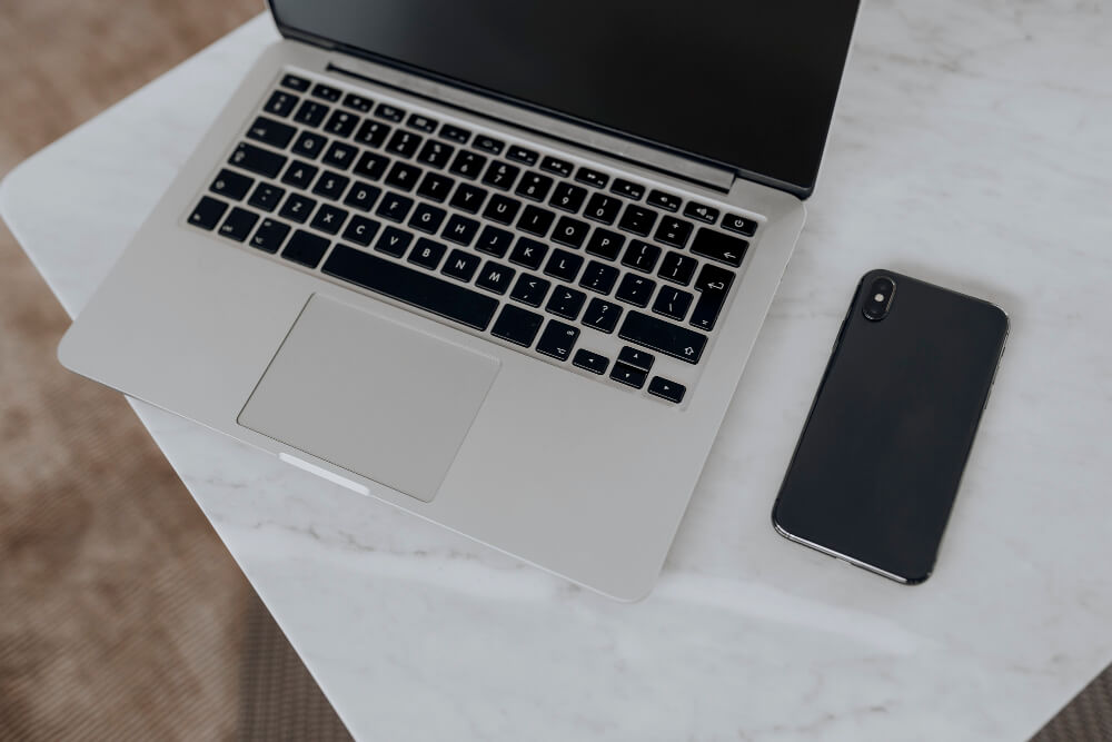 a laptop and smartphone on a marble table