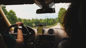 driving-with-phone-map - One Click Root Man driving with a woman in the passenger seat and a map displayed on a phone