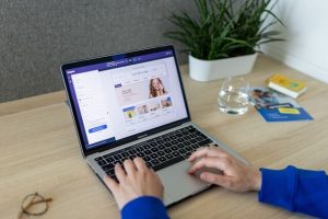 person-shopping-online - One Click Root Laptop displaying an ecommerce site, a man's hands on the keyboard.