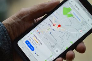 phone-showing-google-maps - One Click Root Person holding a phone with google maps open
