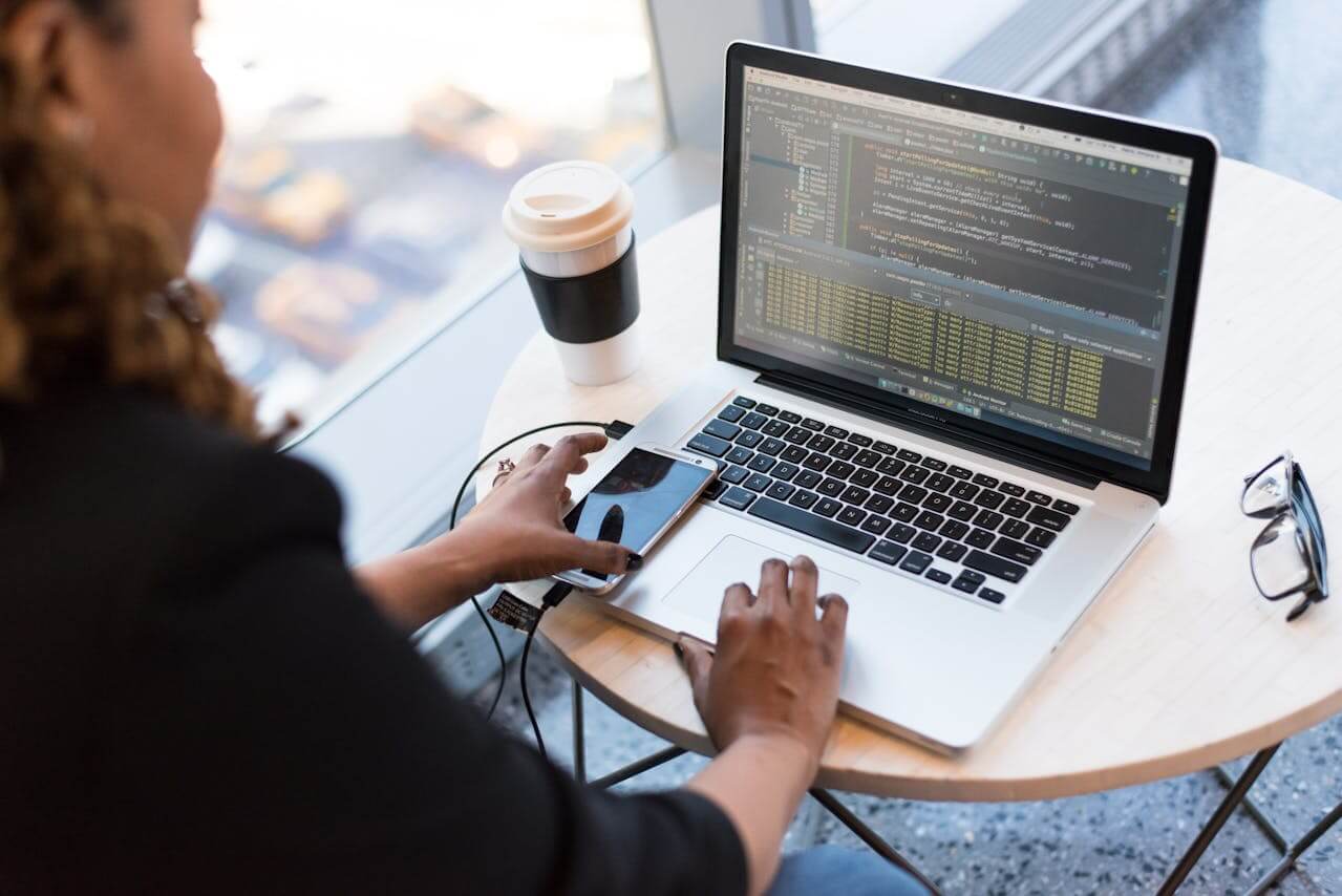 Photo by Christina Morillo on Pexels. Shows a girl using a laptop and phone in a cafe.